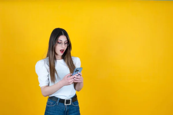 Shocked woman, portrait of excited shocked woman. Surprised caucasian girl holding and using smartphone. Browsing social media, reading a message, emotional young lady facial expression. Copy space.