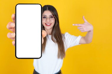 Harika bir uygulama önerisi. Heyecanlı beyaz kadın boş ekran maketi ile akıllı telefon gösterisi yapıyor. Cep telefonunun seçici odağı beyaz ekranı gösteren bulanık bayan.
