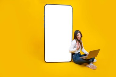 El sallayan bir kadın, el sallayan bir kadın. Merhaba de. Görüntülü arama al. Laptop üzerinde çalış. Kocaman bir akıllı telefon, boş ekran modeli. Uygulama reklam kavramı