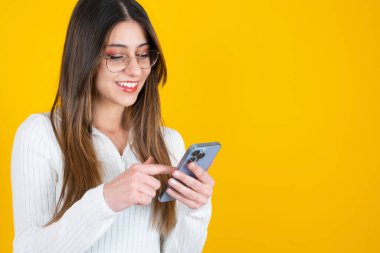 Akıllı telefon kullanarak, akıllı telefon kullanan gülümseyen genç bir kadının fotoğrafını çek. Çevrimiçi sohbet, ekrana dokunma, sosyal medyaya göz atma, mesajlaşma. Mutlu esmer kız modern yaşam tarzı konsepti.