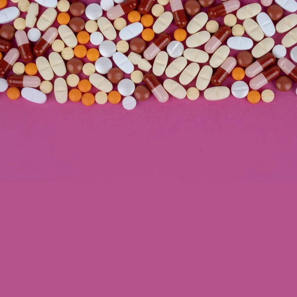 錠剤のフレーム 錠剤のトップビュー画像フレーム 上半分の多色の薬 カプセル ピンクの背景にビタミンがいっぱいです コピースペースとヘルスケアの概念のイメージ 医学的治療 — ストック写真