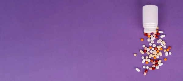 こぼれた丸薬のトップビュー治療薬の概念 カラフルなカプセル 紫色で隔離された薬局の背景 コピースペースエリア付きバナーデザイン 抗生物質ビタミン — ストック写真