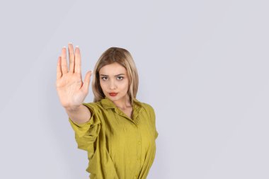 Kes jesti. Avuç içiyle dur işareti yapan genç sarışın kadın. Kızgın, ciddi, üzgün, yüzünde duygular var. İzole açık gri stüdyo arka planı, kopyalama alanı. Reddeden, katı kız. Yaşam tarzı kavramı.