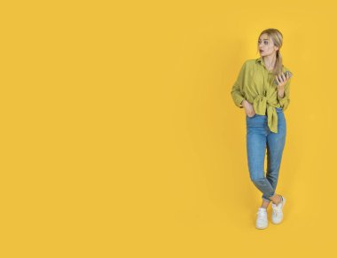 Fotokopi alanını bir kenara bırak, tüm vücudun önüne bak genç Avrupalı sarışın kız fotokopi alanını bir kenara bırak. Cep telefonunu tutmak, akıllı telefon kullanmak. Yönlendirme, pankart, metin çalışma alanı konsepti görüntüsü.