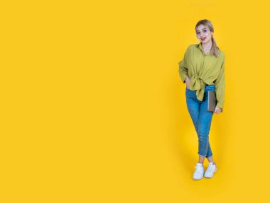 Bilgisayarı kapalı, 20 'li yaşlarda sarışın, beyaz bir üniversite öğrencisi elinde bilgisayarla. Tüm vücut görüntüsü rahatla mutlu gülümseyen kız izole edilmiş sarı arka plan, kopyalama alanı. Pankart tasarımı.