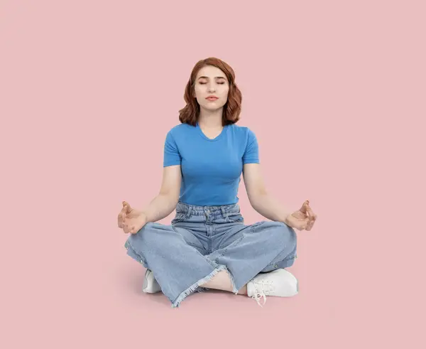Meditating woman, full length body view meditating woman. Sit floor legs crossed, lotus pose with fingers. Concentrating, focusing, finding peace. Redhead bob hair girl. Copy space.