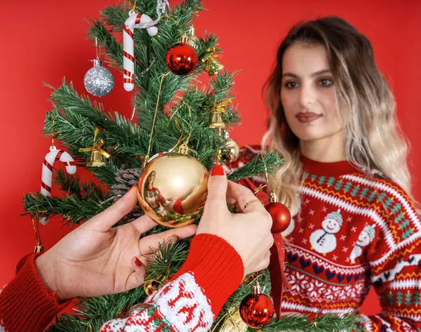 Family decorating Christmas tree, selective focus close up image of woman hand family decorating Christmas tree. Caucasian lady blurred background. Friend winter happy new year eve concept idea.