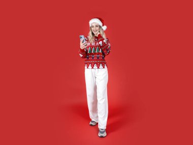 Elinde telefon tutan kadın, elinde telefon tutan beyaz saçlı Noel Baba kadın. Gülümseyen sarışın kız, akıllı telefondan sohbet eden, izole edilmiş kırmızı arka planda duran. Noel, mutlu yeni yıl konsepti.
