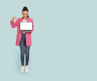 Dizüstü bilgisayar modelini sunuyorum. Beyaz tenli esmer ofis çalışanı dizüstü bilgisayarla sunum yapıyor. Boş ekran defteri tutuluyor. İzole edilmiş turkuaz arkaplan, kopyalama alanı.