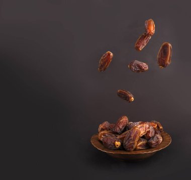 Meyveler tabağa düşüyor. Stüdyo görüntüsü. Meyveler tabağa düşüyor. Kopyalama alanı olan siyah arkaplan. Kutsal Ramazan Kareem ayı İslami kavram fikri imajı. Lezzetli kuru tarihler.