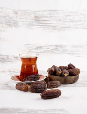 Türk çayı ve bir yığın hurma meyvesi, Ramazan çayı konsepti ve hurma meyvesi. Beyaz ahşap arka plan. Uzayı kopyala Türk halkı için geleneksel İslami yiyecek ve içecek.