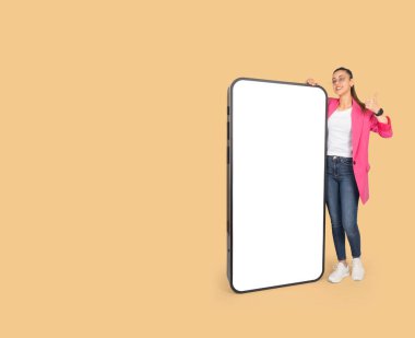 Boş büyük ekran maketi, tam boy heyecanlı iş kadını boş büyük ekran maketi ile dev bir telefonun yanında duruyor. El hareketleriyle hareket ediyor, mobil teklif öneriyor. Yeni uygulama ya da web sitesi. Boşluğu kopyala. 