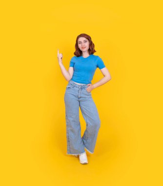 Tam vücut boy, beyaz saçlı güzel bir kız tek el işaret parmağıyla işaret ediyor. Sarı stüdyo arka planında duruyor. Konsept fikir imajı öner. Reklamcılık.