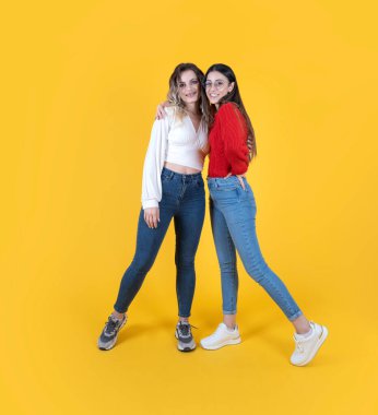 İki kadın poz veriyor, beyaz tenli, çekici iki kadın iyi ruh hali içinde poz veriyor. Kameraya gülümseyen bir kızın diş teli vardı. Sarı stüdyo geçmişi. Uzayı kopyala Halk yaşam tarzı konsepti.