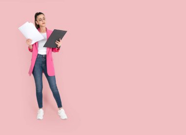 Bayan öğretmen, pembe arka planda duran bayan öğretmenin tüm vücut görüntüsü. Sınav kağıtları ya da ders notları tutuluyor. Eğitim kavramı fikir imajı, kopyalama alanı.