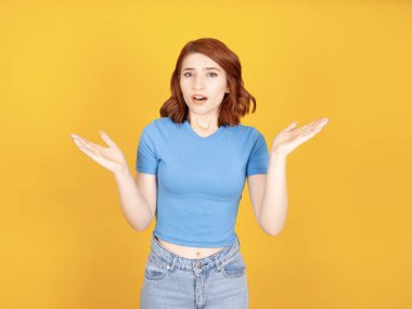 What is your problem? Portrait of young caucasian red bob hair woman pissed-off frustrated say I don't understand what is happened, don't know, confused girl. Isolated yellow background, copy space. 