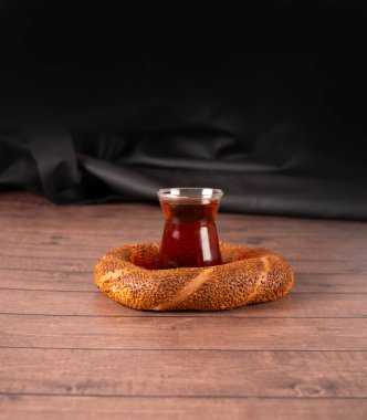 Türk çayı ve simit, Türk çayı ve simit 'in stüdyo konsepti. Ahşap masada susamlı taze pişmiş geleneksel simit ve koyu kahverengi arka plan, kopyalama alanı. Menü fotoğrafı fikri.