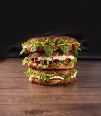 Simit sandviçler, üç tane yan görüş. Simit sandviçleri siyah arka planda, tahta masada yakın plan, kopyalama alanı. Geleneksel Türk fast food kahvaltı fikri reklam imajı.