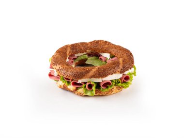 Beyaz peynirli, salamlı, pastırmalı ve beyaz arka planda taze yeşil marullu geleneksel simit sandviçi. Türk pastanesi ürünü susamlı simit, kopyalama alanı.