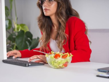 Meşgul iş kadını salatasını yemeyi unutmuş, beyaz kadın ofis çalışanının klavye görünümlü bilgisayar ekranına yazı yazarken görüntüsünü kırpmış. Meşgul girişimci salatasını yemeyi unutmuş..