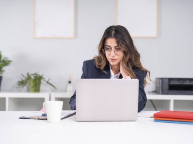 Odaklanmış iş kadını, ciddi Kafkasyalı meşgul esmer 20 'li yaşlarda profesyonel odaklı iş kadını dizüstü bilgisayar görüntülü e-postalar okuyor kadın yönetici ofiste takım elbise giyiyor..