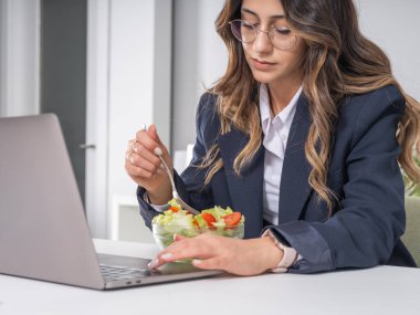 Ofiste salata yemek, ofiste salata yiyen sağlıklı bir iş kadınının beyaz görünümünü kapatmak. İşte öğle yemeği kavramı, çalışırken sağlıklı beslenme..