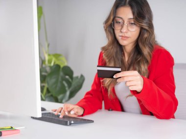 Kredi kartı tutuyor, Kafkasyalı genç bir iş kadını elinde bilgisayar klavyesi kullanarak kredi kartı tutuyor. Çevrimiçi alışveriş, e-ticaret, internet bankacılığı, para harcama konsepti imajı.
