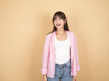 Mutlu, genç, beyaz tenli, heyecanlı, esmer, 20 'li yaşlarda bir kadın bej rengi stüdyo arka planında tek başına duruyor. Üzerinde beyaz bluz pantolon, fotokopi alanı tanıtım alanına bakıyor. Halk yaşam tarzı konsepti.