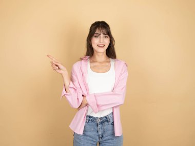 Kadın işaret parmağı fotokopi alanı bir yana, genç beyaz esmer portresi kendinden emin 20 'li yaşlarda kadın işaret parmağı bir yana fotokopi alanı ticari tanıtım alanı, bej arka plan..