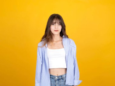 20 'li yaşlarda, sarı stüdyo arka planında izole edilmiş beyaz tişörtlü, sıradan giysili, fotoğraf makinesi görünümlü, gülümseyen genç beyaz esmer kadın portresi. Yaşam tarzı kavramı.