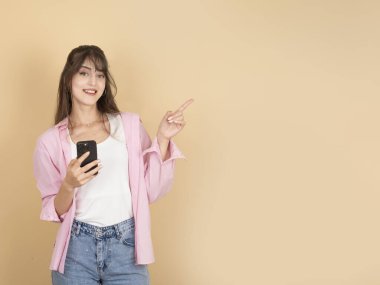 Özel online teklif konsepti. Bej arka planda cep telefonu kullanan 20 'li yaşlardaki esmer kadının portresi tanıtım alanının boş olduğunu gösteriyor..