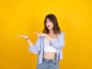 Kadın işaret parmağı açık avuç içi, genç beyaz mutlu gülümseyen organizatör 20 'li yaşlarda kadın işaret parmağı açık, fotokopi alanı dışında sarı arka planda izole edilmiş bir alan..