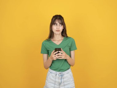 Düşünceli genç kadın, genç Kafkas 20 'li yaşlarda düşünceli genç kadın. Düşünceli, üzgün bir yüzün, izole edilmiş sarı kopya alanına baktığını düşünerek cep telefonu yazma mesajı kullan..