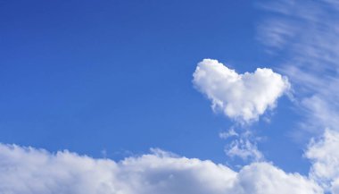 Mavi gökyüzünde kalp şeklinde bulut ve metin alanı