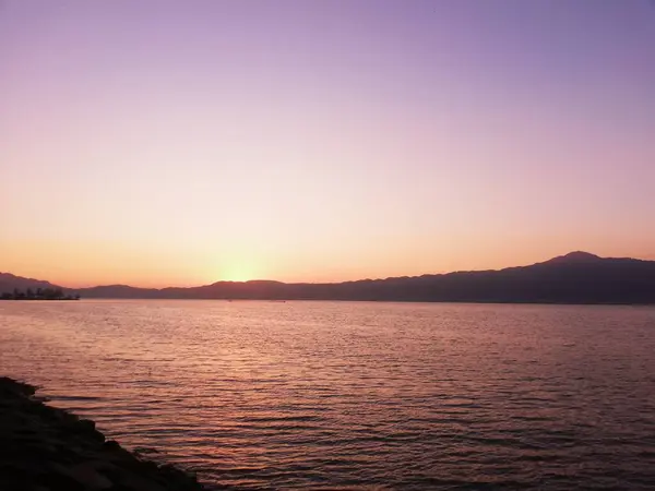 Sunset over the lake with reddish-purple sky and mountain silhouettes