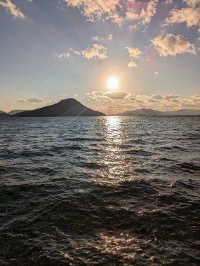 Güzel gün batımı dikey, deniz ve dağların silueti güneş batarken