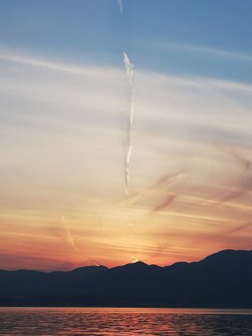 Gölde gün batımı ve gizemli bir atmosfer ile bulutlar yükseliyor.