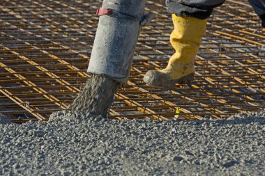 İnşaat işçisi beton pompa kullanarak inşaat demirine beton döküyor