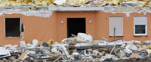 Önplanda enkaz olan yıkılmış ev panoramik biçimdeName