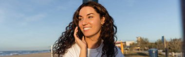 Barcelona sahilinde akıllı telefondan konuşan neşeli genç kadın, afiş. 