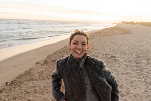 stock image Cheerful young woman looking at camera on beach in evening 