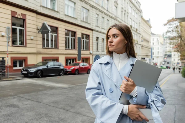 Όμορφη Γυναίκα Μπλε Καμπαρντίνα Κρατώντας Smartphone Και Laptop Ενώ Περπάτημα — Φωτογραφία Αρχείου