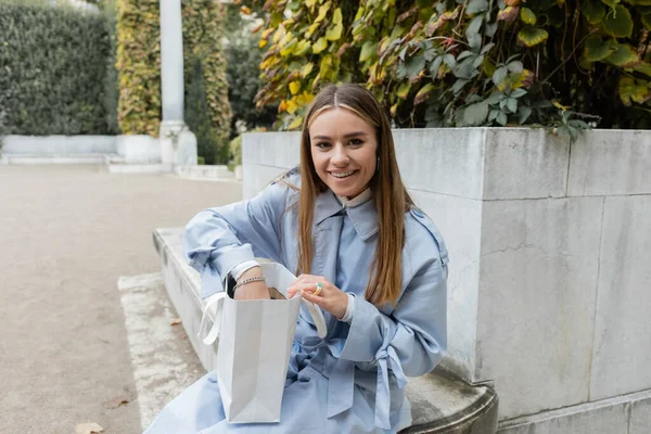 Mujer Joven Feliz Con Gabardina Azul Sentada Con Bolsa Papel — Foto de Stock