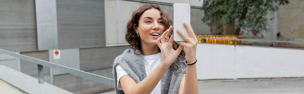 Usmívající Mladá Kudrnatá Žena Teplým Svetrem Ramenou Video Chat Smartphonu — Stock fotografie