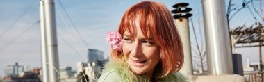 banner of happy attractive woman with flower in hair looking away on roof terrace in Vienna, Austria clipart