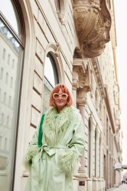 Sokak modası, son moda güneş gözlüklü kadın gezgin Viyana, Avusturya 'da şehir caddesinde yürüyor.