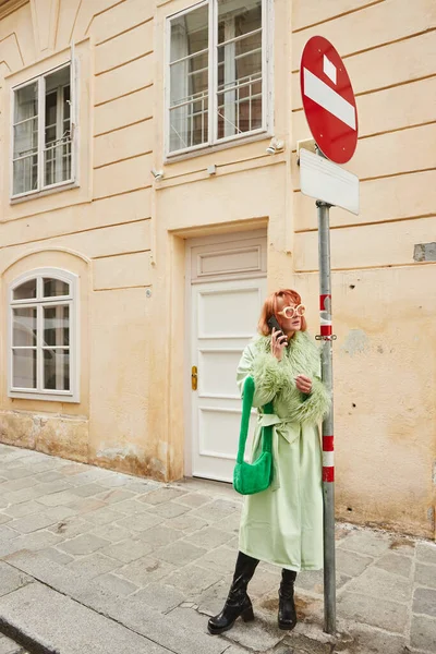 stock image fashionable woman in sunglasses and casual attire talking on smartphone on urban street in Vienna