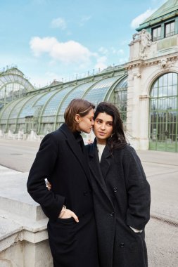 Paltolu genç lezbiyen çift Viyana 'da Palmenhaus ile yakın kucaklaşmayı paylaşıyor.