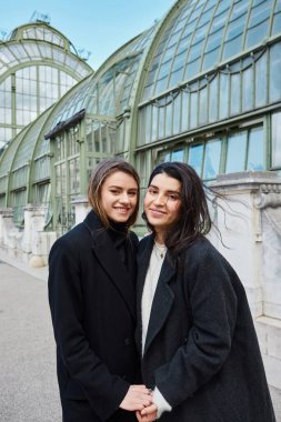 Viyana 'da Palmenhaus yakınlarında dikilirken ceketli neşeli Lgbt çifti
