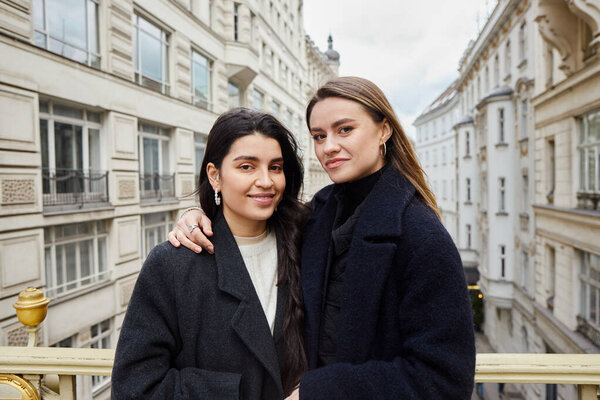 Интимный момент на балконе с видом на архитектуру города, как обратная сторона, счастливые влюбленные лесбиянки